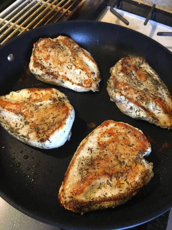 Chicken breasts seasoned with herbs cooking successful  a skillet connected  a stovetop