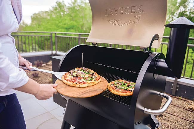 a model making pizza on a traeger grill