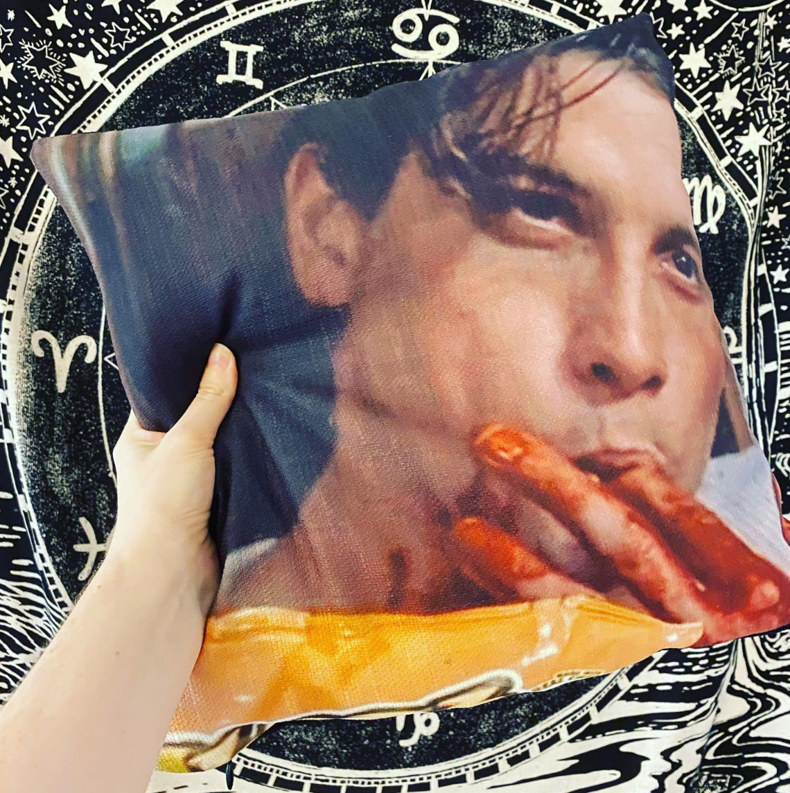 hand holding photo pillow with meme of Skeet Ulrich of Scream licking fingers of fake blood but it looks like hot cheetos dust