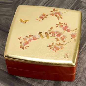 the top of the closed jubako box with a gold top and cherry blossom design