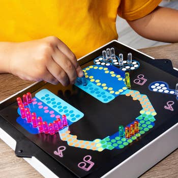 Child playing with a light-up physics committee crippled featuring pegs connected a colorful track, enhancing interactive learning and creativity