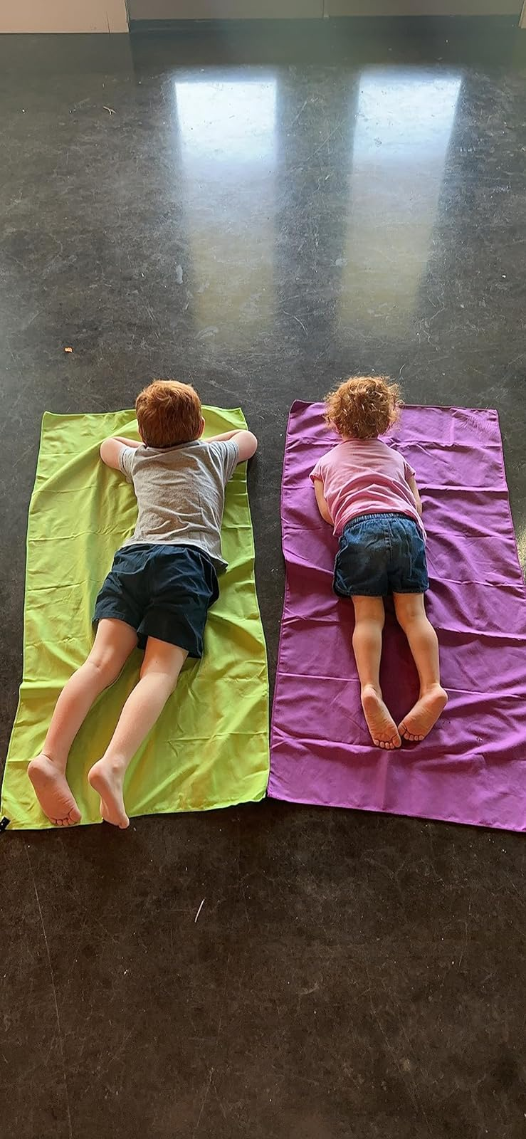 a reviewer's two kids laying on a green and purple towel