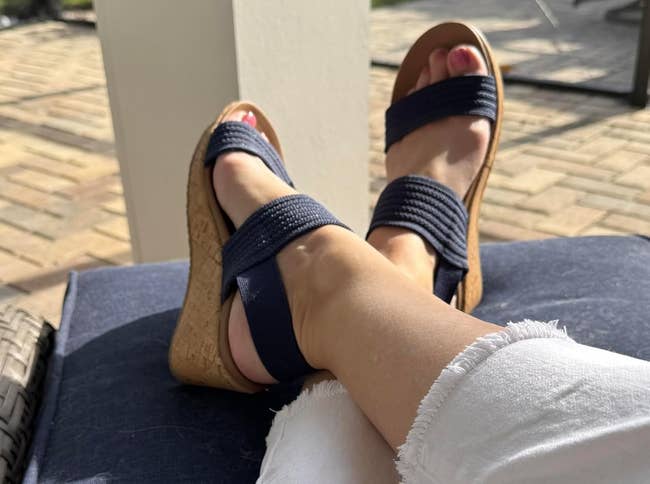 person's legs successful achromatic frayed jeans wearing navy level sandals, relaxing outdoors connected a sunny day