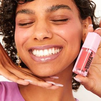 model wearing the pink blush and holding a tube of it
