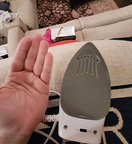 reviewer holding their hand next to the iron showing the iron plate is about the size of their palm
