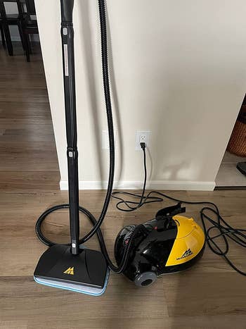 Reviewer image of black and yellow steam mop plugged in 