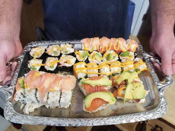 reviewer holding a platter of sushi prepared with the kit