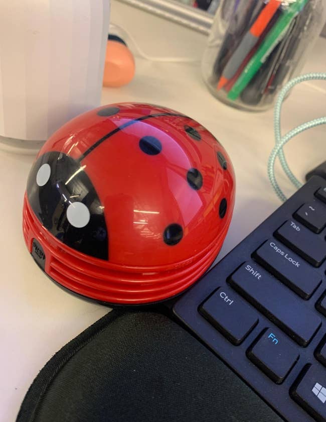 reviewer image of the red ladybug mini vacuum on their desk next to their keyboard