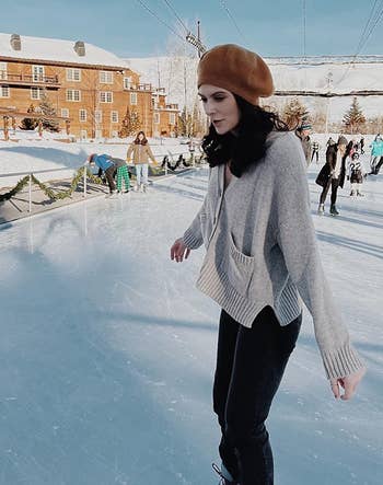 reviewer wearing the gray cardigan with black pants while ice skating