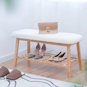 the white bench holding two pairs of shoes on its lower shelf and a purse on top