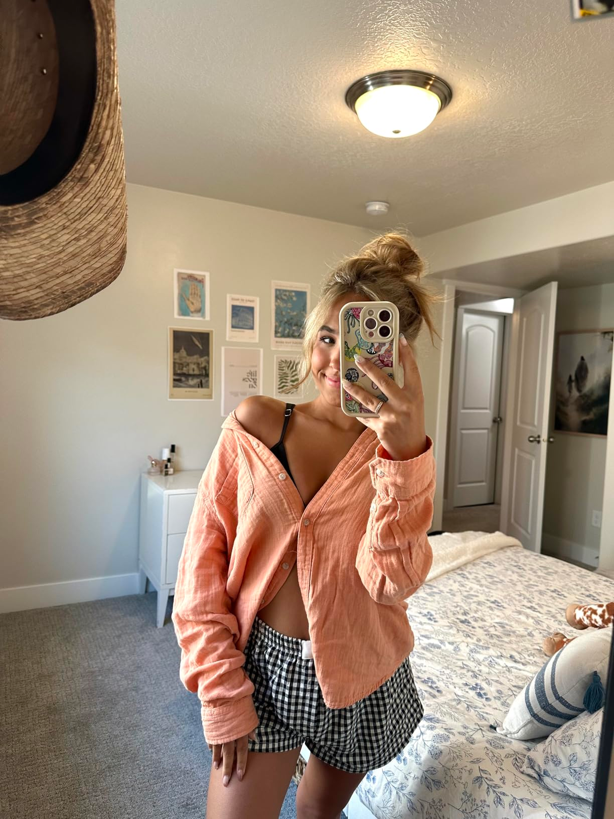 Person successful  a casual outfit with a escaped   blouse and checkered shorts taking a selfie successful  a chamber  with partition  creation  and decor