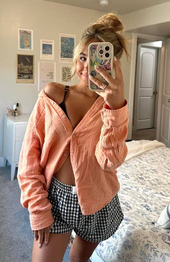 Person successful a casual outfit with a escaped blouse and checkered shorts taking a selfie successful a chamber with partition creation and decor