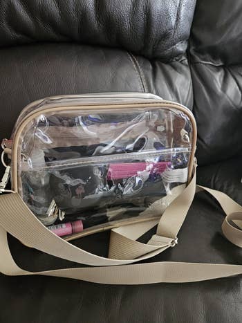 Clear crossbody bag on a chair, displaying visible items inside, such as a case and lipstick, suitable for organized storage while shopping