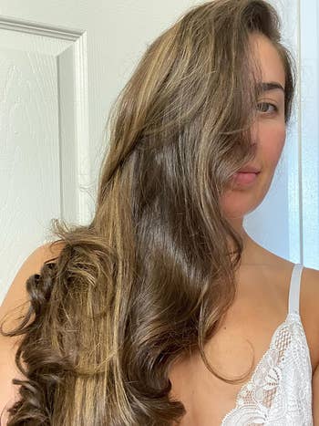 A reviewer with long, brown, shiny hair after using the treatment