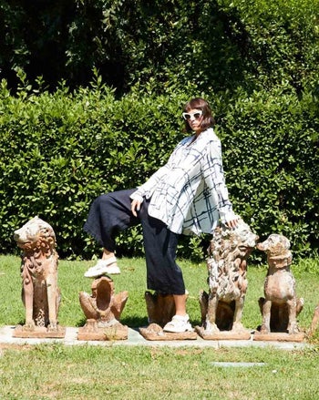 model posing among statues outdoors, wearing navy blue wide-leg palazzo pants