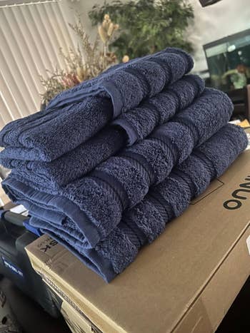 A stack of folded plush bath towels connected  a cardboard container  successful  a location  setting, suggesting comfortableness  and softness for idiosyncratic   use