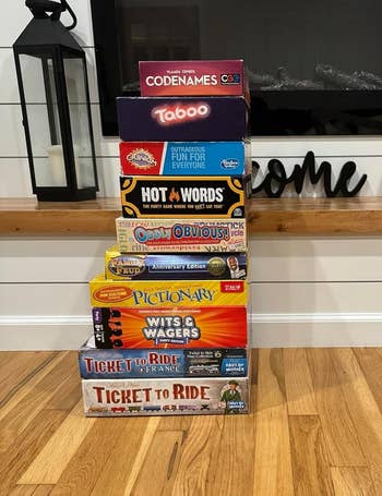 Stack of various family board games including Codenames, Taboo, Hot Words, Oddly Obvious, Pictionary, Wits & Wagers, and Ticket to Ride