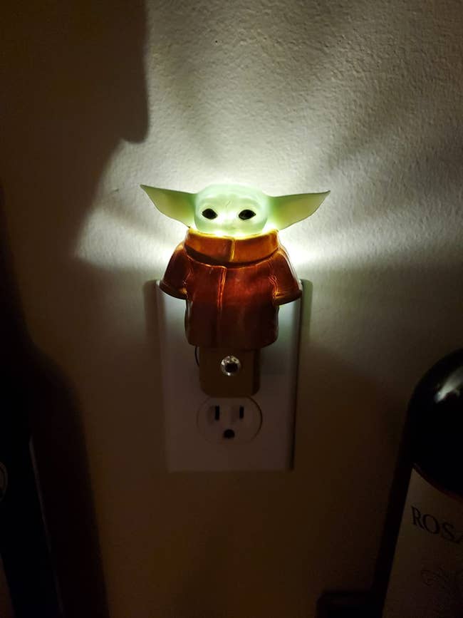 a baby yoda nightlight plugged into the wall