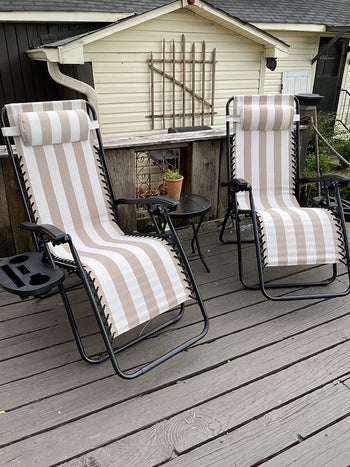 reviewer photo of the two recliners in a white and beige striped print on a deck