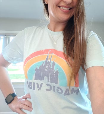 a reviewer in a white tee with a rainbow on it and the castle with 