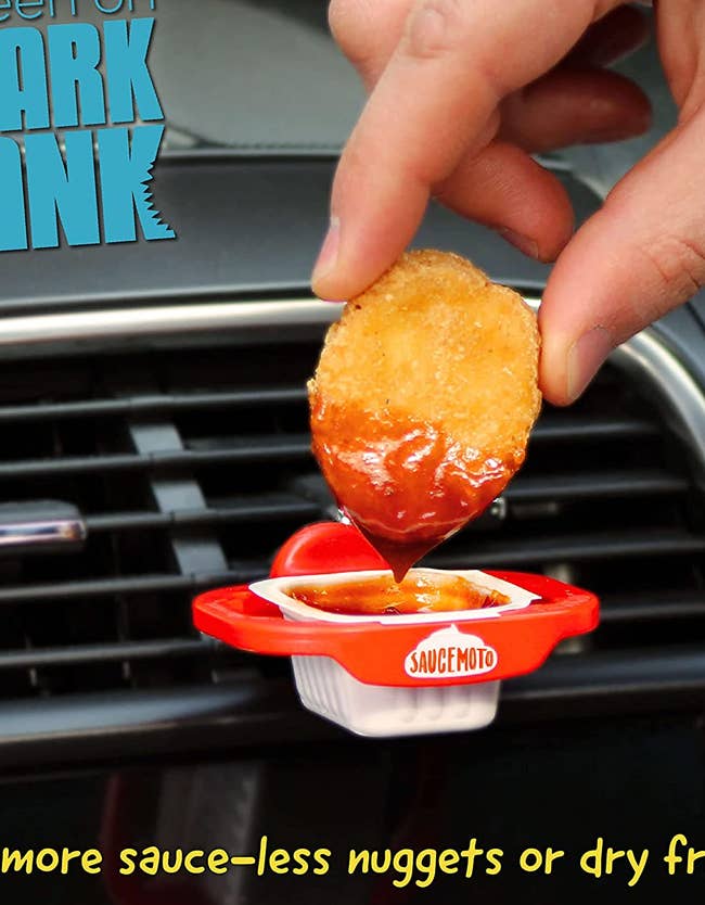 hand dunking a chicken nugget into barbecue sauce that’s sitting in the dip clip