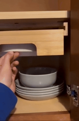 Person pulling paper plates out of an installed bamboo holder under a cabinet