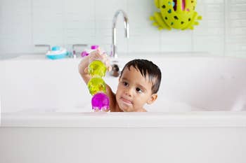 another child stacking the toys on the rim of a bathtub
