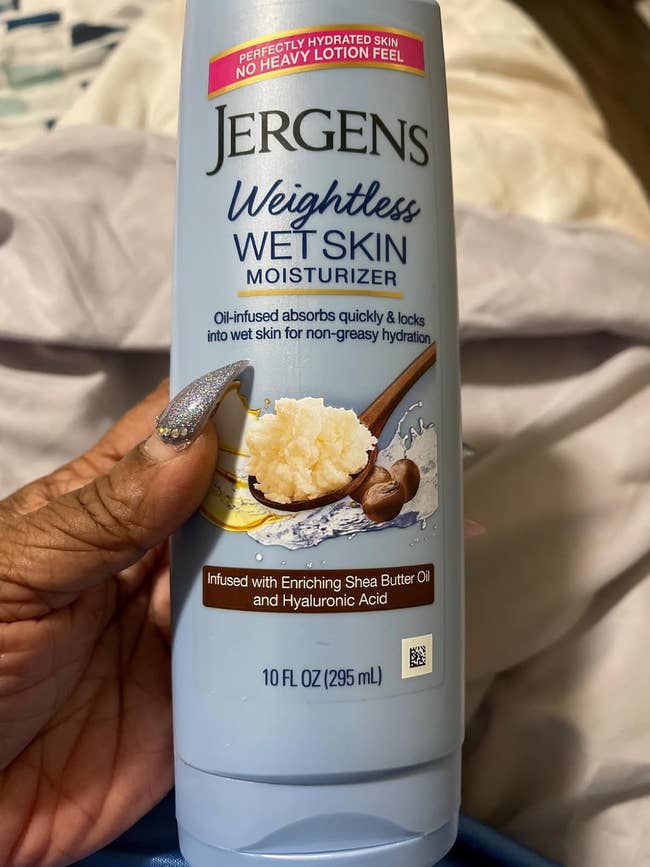 A manus  holds a vessel  of Jergens Weightless Wet Skin Moisturizer