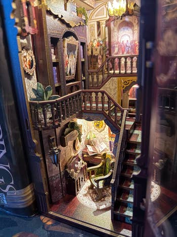 Intricate book nook interior featuring a detailed staircase, art, and furniture.