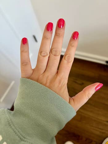 buzzfeed editor's hand showing their brightly colored olive and june manicure