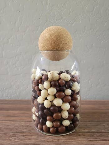Glass jar with a round cork lid that's fully of jelly beans 