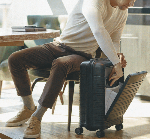 man putting laptop inside pop-out front pocket of suitcase