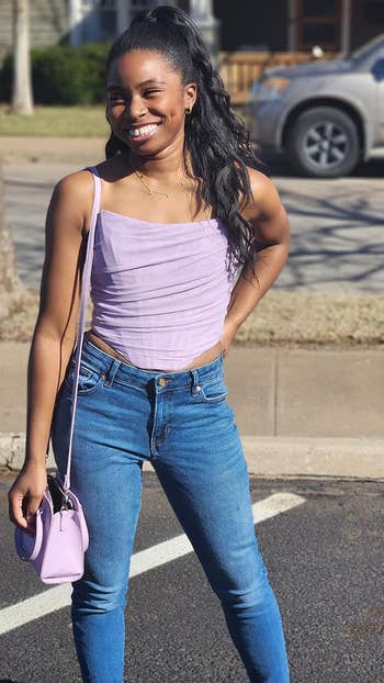 person in a lavender corset top and jeans 