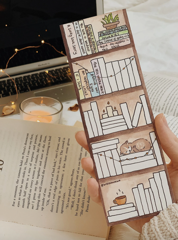 Image of someone holding the bookmark next to a book