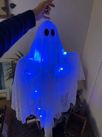 reviewer holding up the blue glowing ghost up close