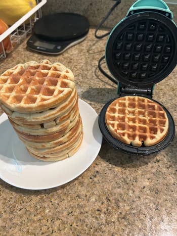 reviewers waffle maker with a waffle in it next to a stack of waffles