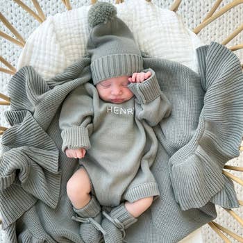 an infant in a blue-grey personalized sweater romper