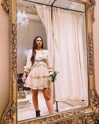 reviewer at wedding dress shop looking at outfit in large mirror