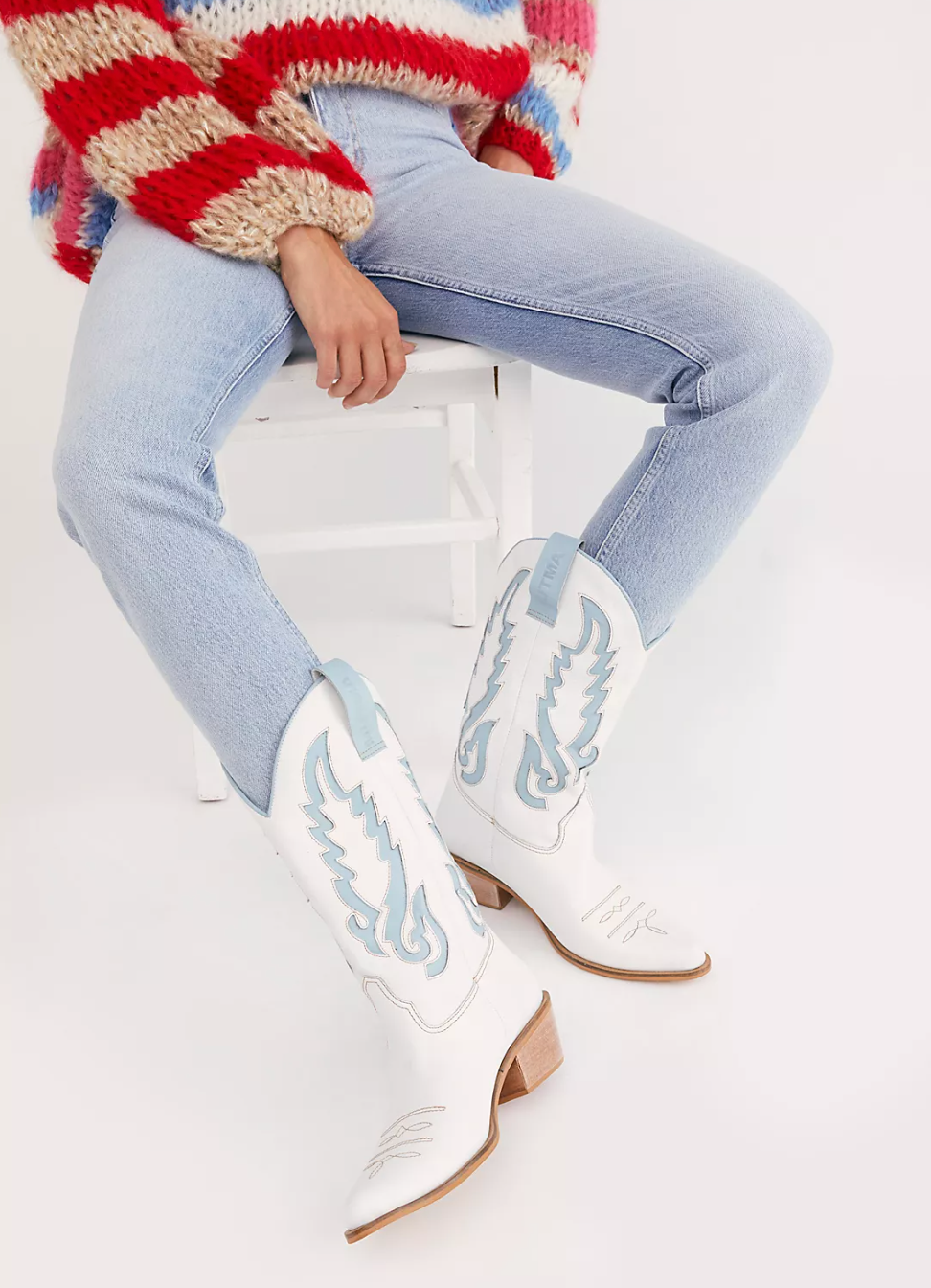Model wearing jeans with white and light blue cowboy boots 