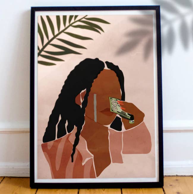 Framed artwork depicting a stylized silhouette with braided hair wiping tears with money