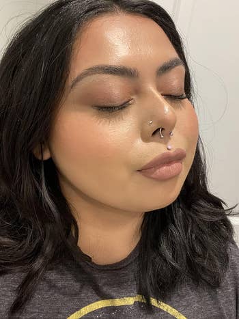 a brown reviewer wearing a full face of makeup set with the spray
