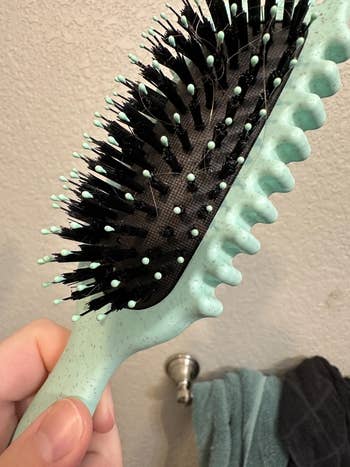 Close-up of a manus  holding a hairbrush with grooved edges 