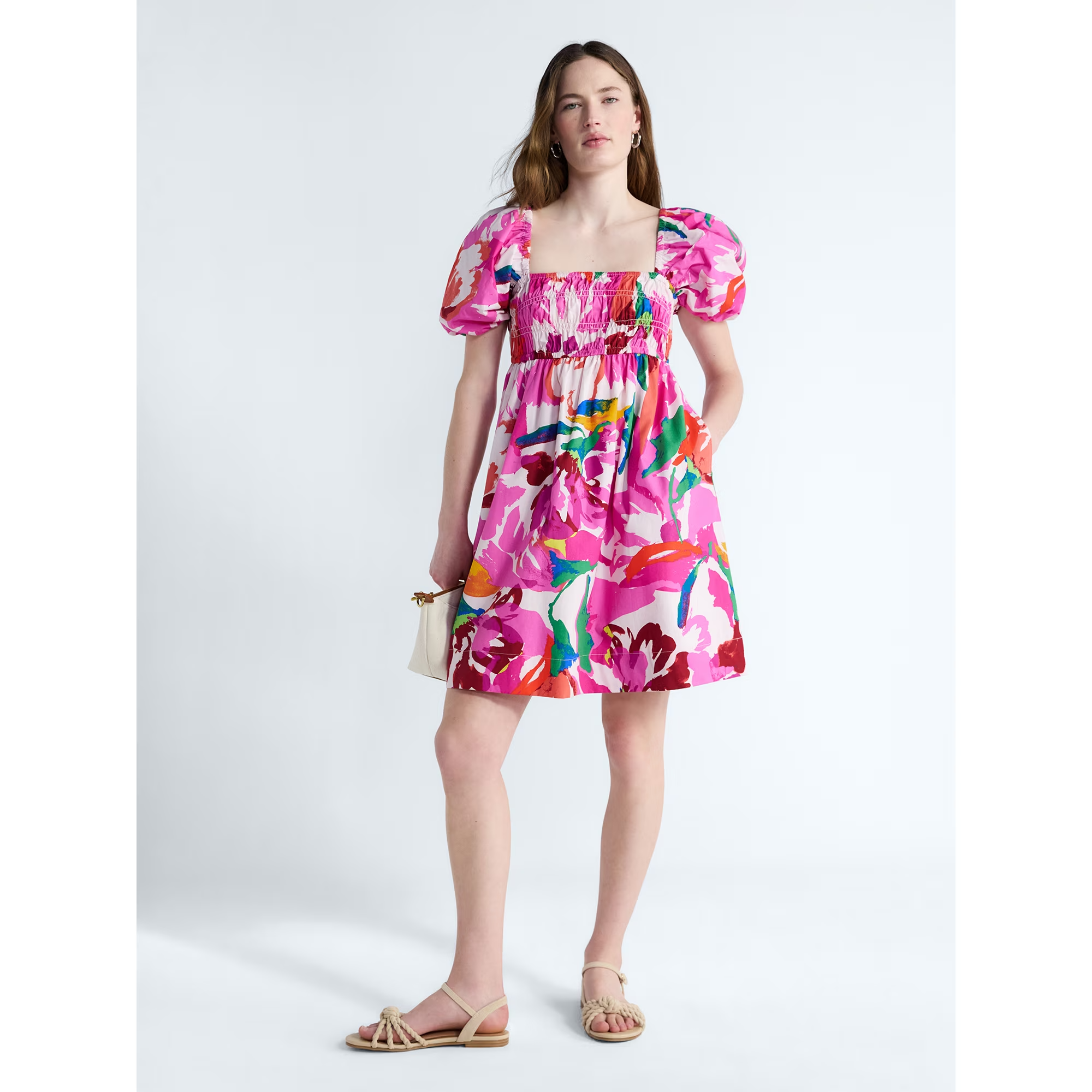 Person wearing a floral people     formal  with puff sleeves, holding a tiny  bag, and wearing sandals