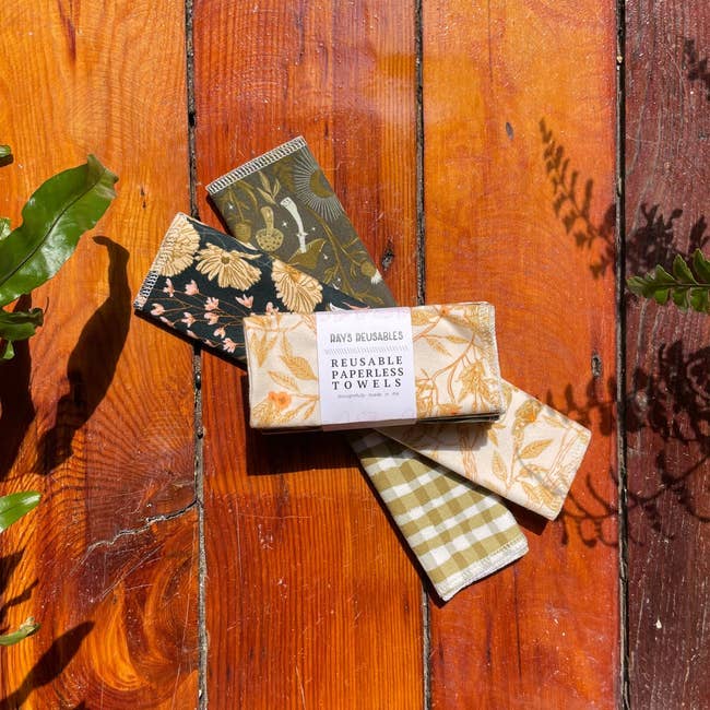 Reusable paperless towels successful  assorted prints, including floral and gingham, displayed connected  a woody  aboveground  with works  leaves