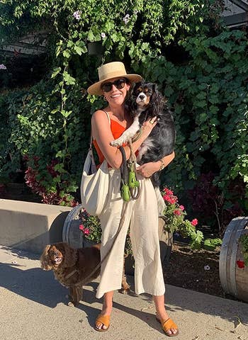 reviewer wearing the beige linen pants while holding dog