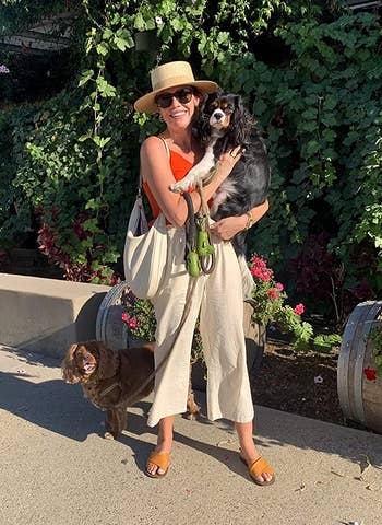 reviewer wearing the beige linen pants while holding dog