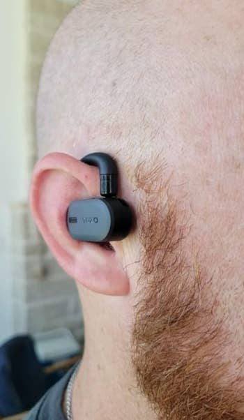Close-up of a reviewer wearing a black wireless earbud in their right ear