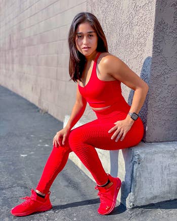 reviewer wearing the leggings in a bright red color with matching sports bra and sneakers