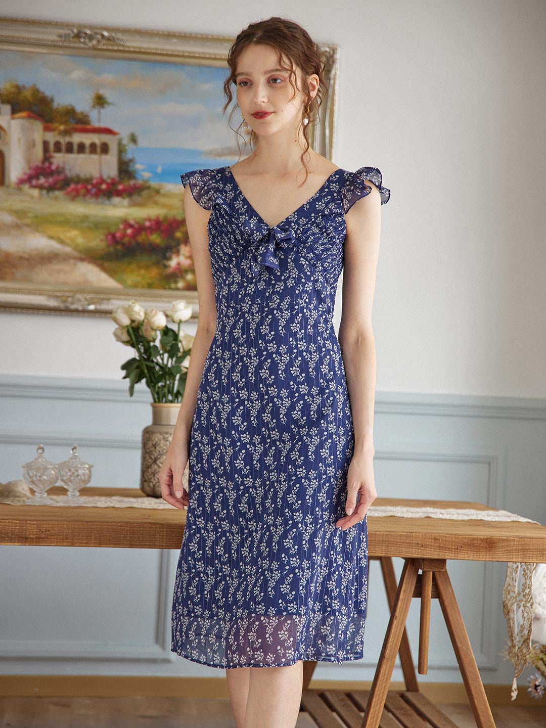 model wearing the v-neck ruffle sleeve dress in navy blue with white flowers all over it