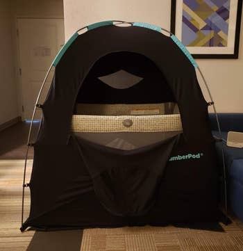 a reviewer photo of the SlumberPod with the front zip door open showing a play peen inside 